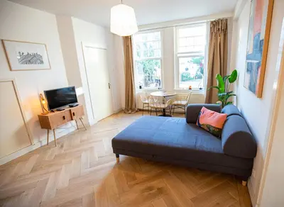 a living room with a blue couch and a wooden floor at Cute Beach House Zandvoort in Zandvoort