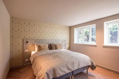 a bedroom with a bed and two windows at De Kievit in Vogelenzang