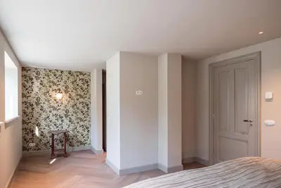 a bedroom with a bed and a wall with floral wallpaper at De Kievit in Vogelenzang