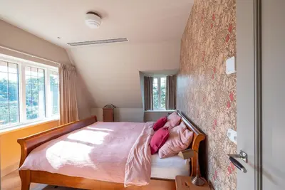 a bedroom with a bed with pink sheets on it at De Kievit in Vogelenzang