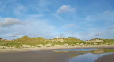 a view of a beach with mountains in the background at Zomerhuis Duinzicht in Egmond aan den Hoef