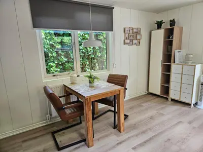 a dining room with a table and two windows at Zomerhuis Duinzicht in Egmond aan den Hoef