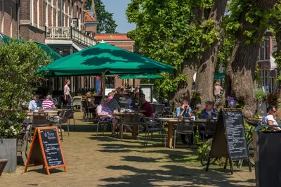 a group of people sitting at tables under a green umbrella at Silver Moon Bed & Breakfast in Voorschoten