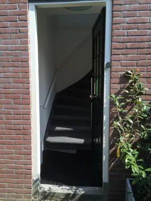 a stairway with a black door in a brick building at Studio De Laan in Zandvoort