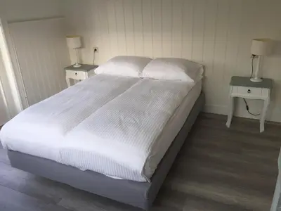 a bedroom with a large white bed with two tables at Studio De Laan in Zandvoort
