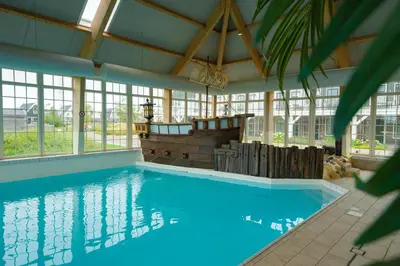 a large swimming pool in a building with windows at EuroParcs Poort van Amsterdam in Uitdam