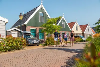 a family standing in front of a house at EuroParcs Poort van Amsterdam in Uitdam