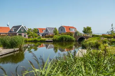 a river with houses and a bridge at EuroParcs Poort van Amsterdam in Uitdam