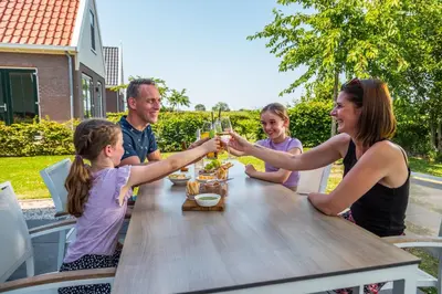 a family sitting at a table drinking glasses of wine at EuroParcs Poort van Amsterdam in Uitdam