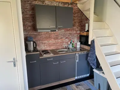 a small kitchen with a sink and a brick wall at Appartement - B&B de Koog in Uitgeest