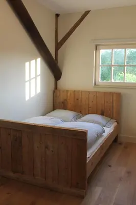 a large wooden bed in a room with a window at Rest & Rust in Werkhoven