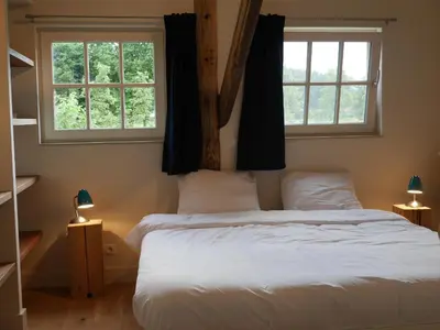 a bedroom with a large bed with two windows at Rest & Rust in Werkhoven