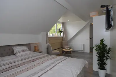 a bedroom with a large white bed in a attic at B&B De Kaagse Boer in Kaag