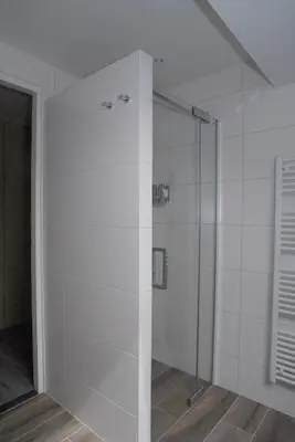 a glass shower in a bathroom with white tiles at B&B De Kaagse Boer in Kaag