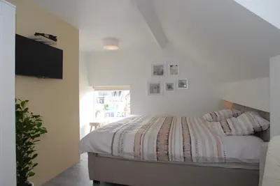 a white bedroom with a bed and a window at B&B De Kaagse Boer in Kaag