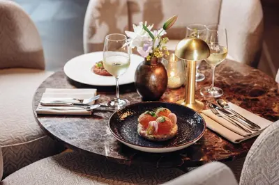 a table with a plate of food and glasses of wine at Van der Valk Hotel Oostzaan - Amsterdam in Oostzaan