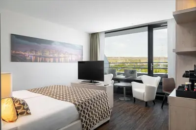 a hotel room with a bed and a desk with a television at Van der Valk Hotel Oostzaan - Amsterdam in Oostzaan
