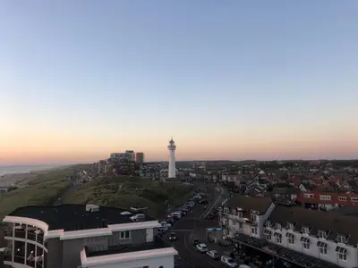 a lighthouse on top of a hill with a city at Coastal Dreaming in Egmond aan Zee