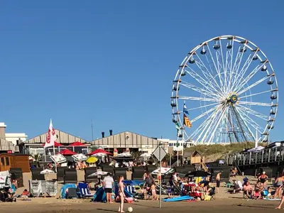 a ferris wheel and a crowd of people at a beach at Coastal Dreaming in Egmond aan Zee