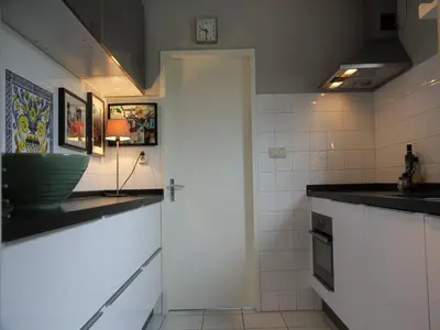 a kitchen with white cabinets and a door in it at Groet Villa Stay with Garden Views in Groet
