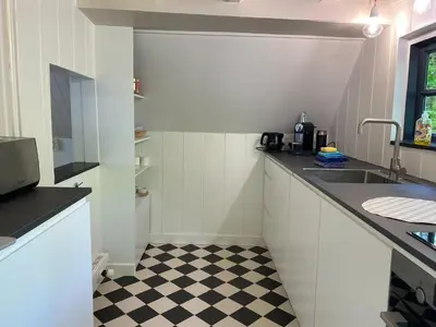 a kitchen with white cabinets and a checkered floor at Holiday Home in Bergen near the Beach in Bergen