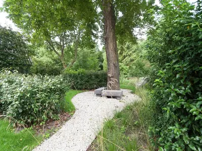 a bench sitting next to a tree on a path at Holiday Home in Bergen near the Beach in Bergen