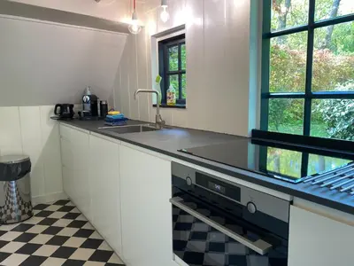 a kitchen with white cabinets and a black counter top at Holiday Home in Bergen near the Beach in Bergen
