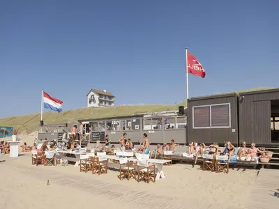 a group of people sitting at tables on the beach at Holiday Home in Bergen near the Beach in Bergen