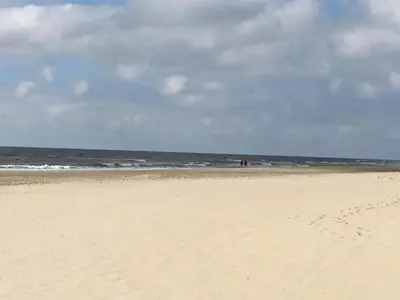 a sandy beach with a person flying a kite at Holiday Home in Schoorl near Forest & Beach in Schoorl