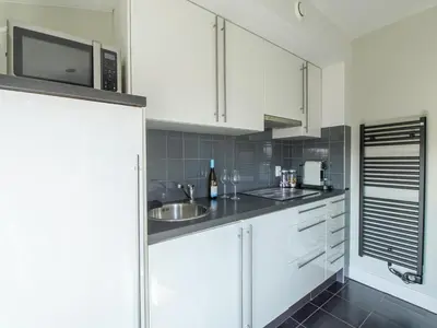 a kitchen with white cabinets and a sink and a microwave at Apartment in Katwijk near the Beach in Katwijk