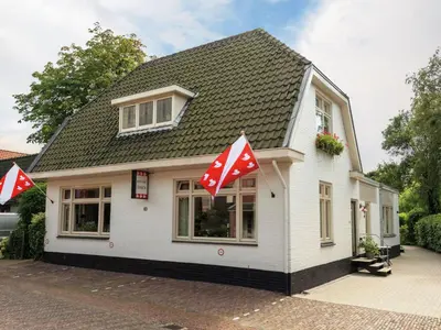 a small white house with red and white flags on it at Apartment in Bergen near Sandy Beaches in Bergen