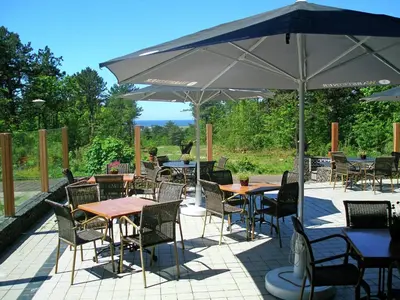 a patio with tables and chairs under an umbrella at Apartment in Bergen aan Zee near the Beach in Bergen aan Zee