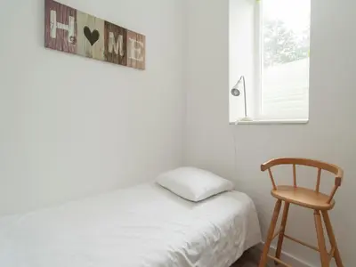 a bedroom with a bed and a chair and a window at Apartment in Bergen aan Zee near the Beach in Bergen aan Zee