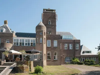 a large red brick building with a tower at Apartment in Bergen aan Zee near the Beach in Bergen aan Zee