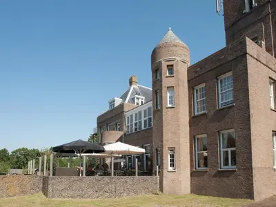 a large brick building with an umbrella in front of it at Apartment in Bergen aan Zee near the Beach in Bergen aan Zee