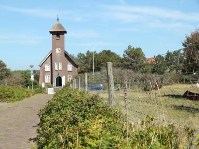 an old brick building with a tower in a field at Apartment in Bergen aan Zee near the Beach in Bergen aan Zee