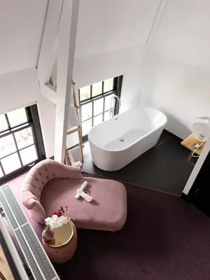 a bathroom with a bath tub and a pink chair at Wolf Hotel Kitchen & Bar in Alkmaar
