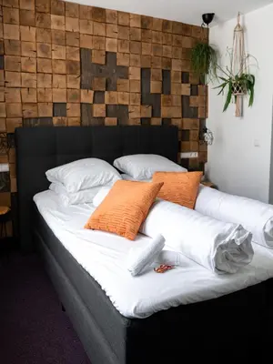 a bed with orange and white pillows on it at Wolf Hotel Kitchen & Bar in Alkmaar