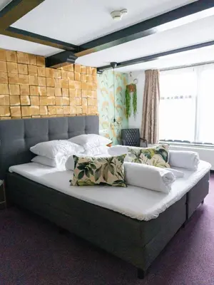 a bedroom with a large bed with white sheets and pillows at Wolf Hotel Kitchen & Bar in Alkmaar