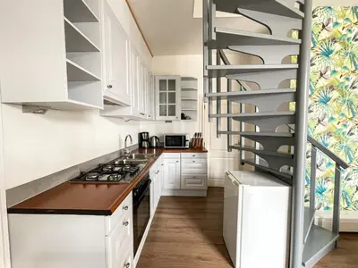 a kitchen with white cabinets and a spiral staircase at Mio appartementen in Zandvoort