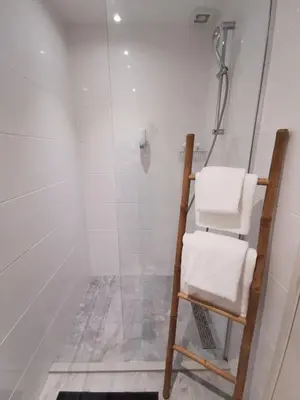 a shower with a glass door and a chair in a bathroom at Mio appartementen in Zandvoort