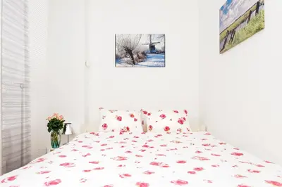 a white bed with red flowers on it in a bedroom at GH Amsterdam in Amsterdam