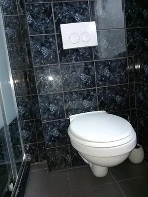 a bathroom with a toilet and a black tiled wall at Studio Slijterij Zandvoort in Zandvoort