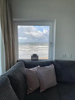 a living room with a couch and a large window at Dreamview Apartment in Zandvoort