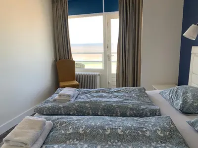 a hotel room with two beds and a window at Dreamview Apartment in Zandvoort