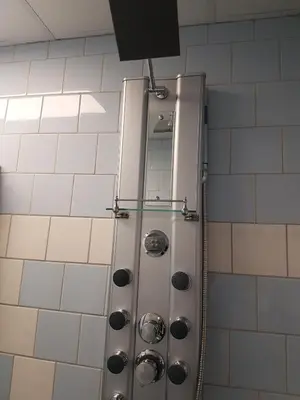 a shower in a bathroom with white tiles at Appartement De Molshoop II in Landsmeer