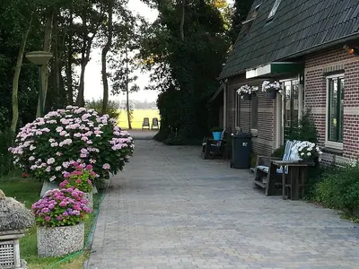 a brick walkway next to a building with flowers at Appartement De Molshoop II in Landsmeer