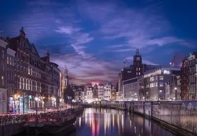 a city at night with a river and buildings at Luxury Flower Market Apartment in Amsterdam
