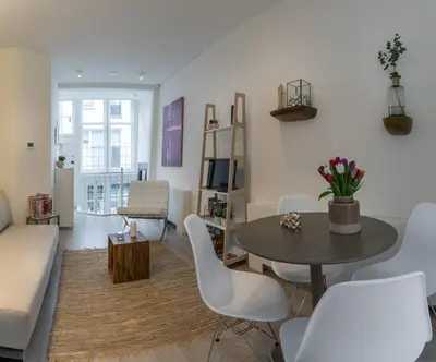 a living room with a table and white chairs at Luxury Flower Market Apartment in Amsterdam