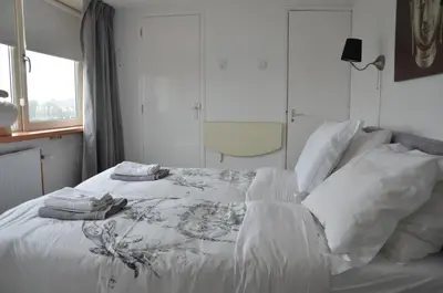 a white bed with white sheets and pillows on it at Pension 't hofje 350 meter van het strand in Noordwijk aan Zee